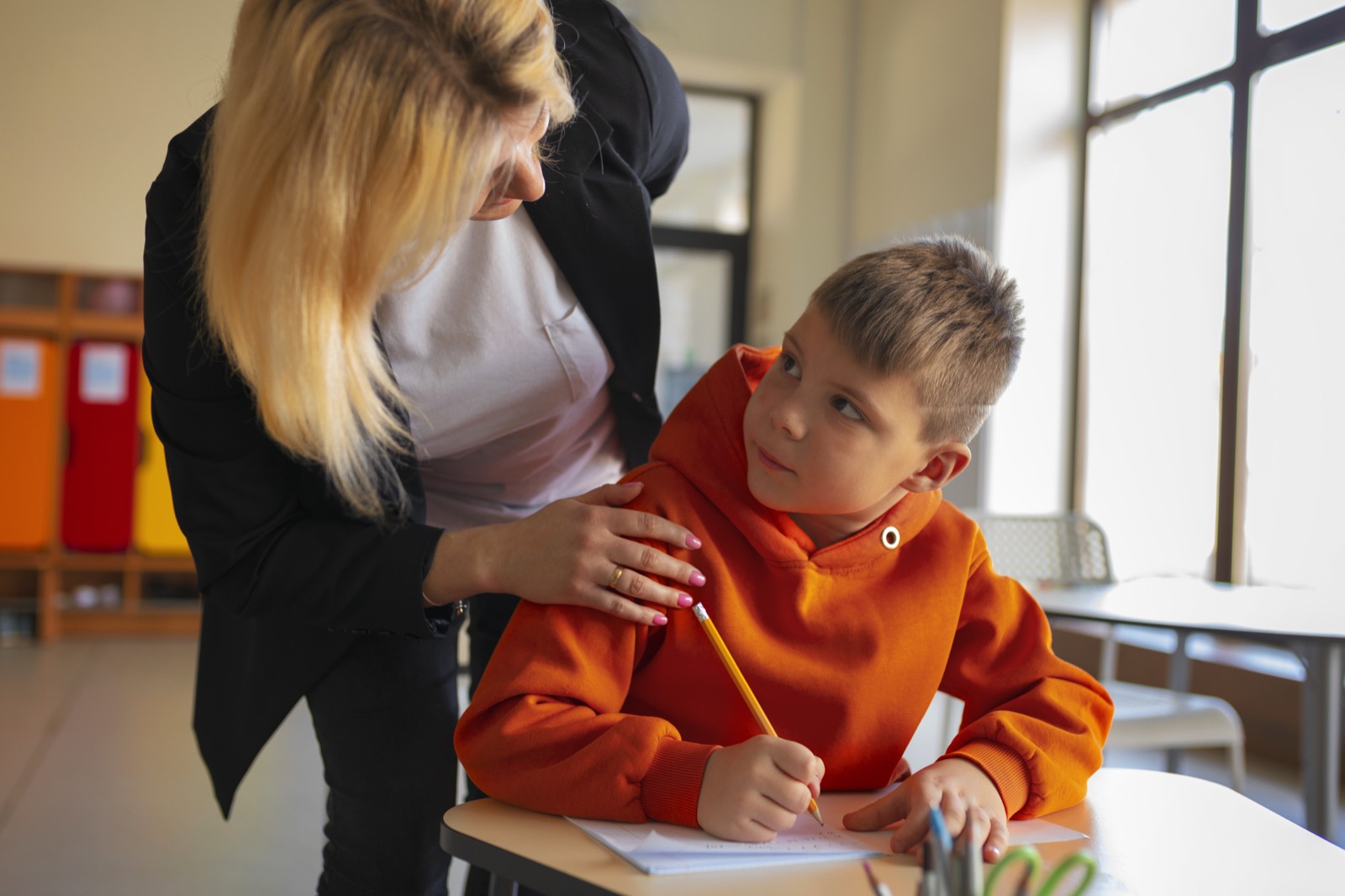 Leerkracht begeleidt een leerling in de klas
